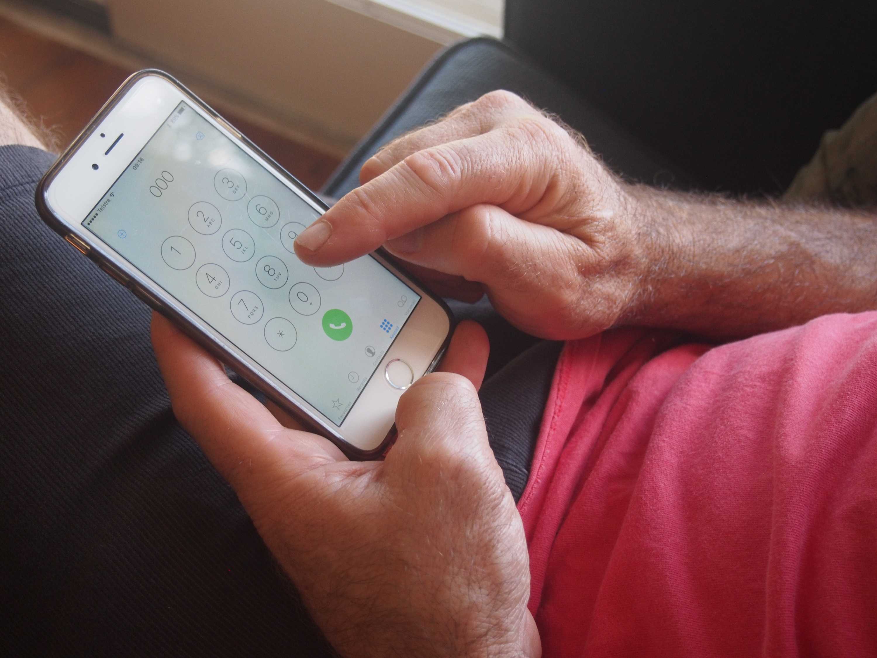 Close da mão do homem discando 000 no iphone