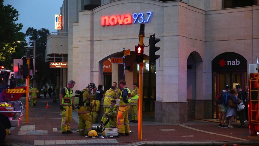 A group of fire fighters standing in front of a  building with Nova 93.7 neon sign