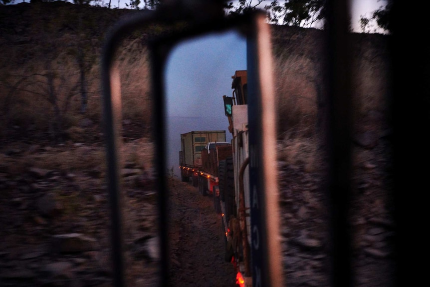 a view of the trucks mirror on dusk showing all three trailers