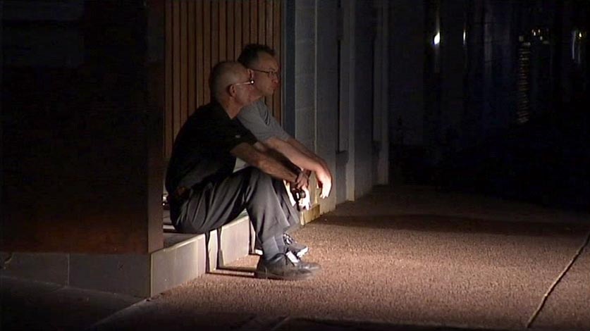 Two men sit in a Darwin street during a blackout in the city.