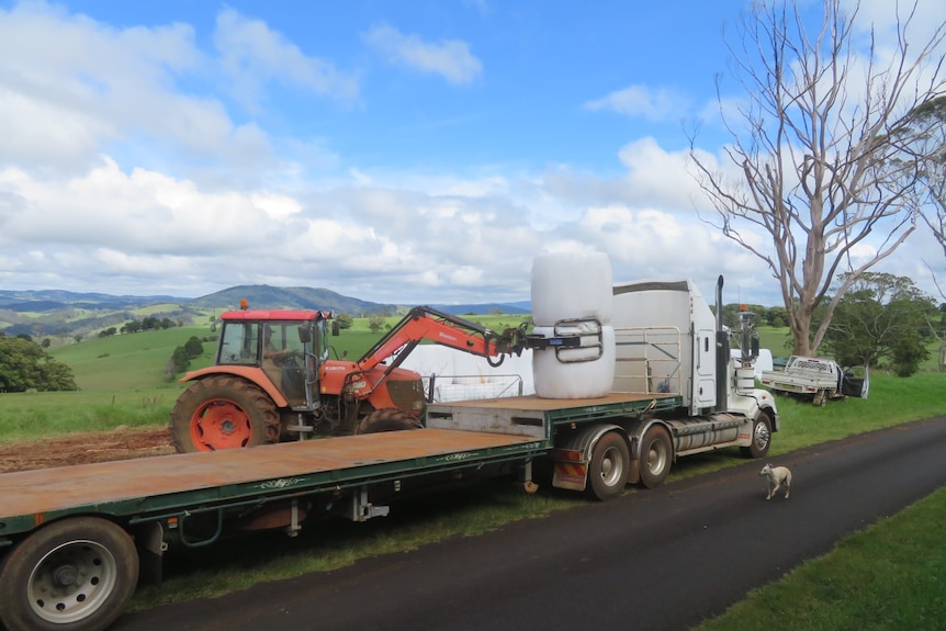 Truck being loaded with silage bales with mountains and sky in background