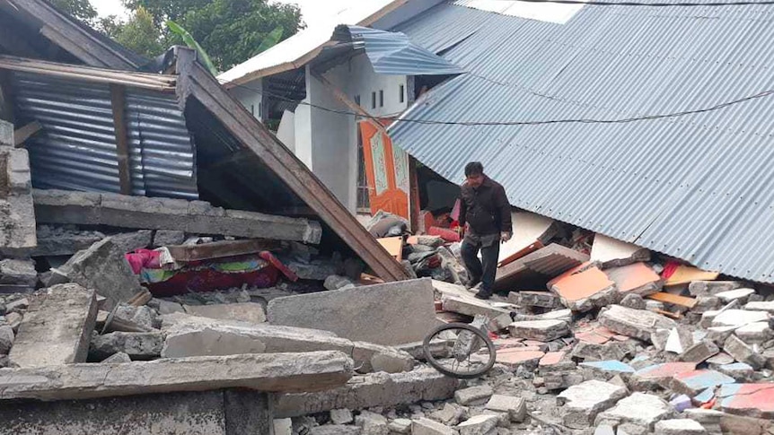 A man walks through debris from destroyed houses