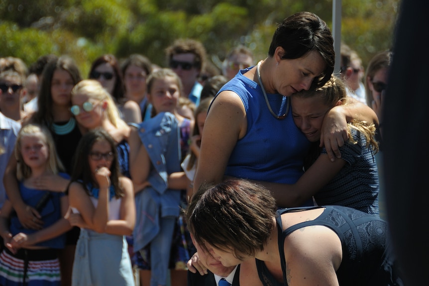 Two people hug at a funeral.