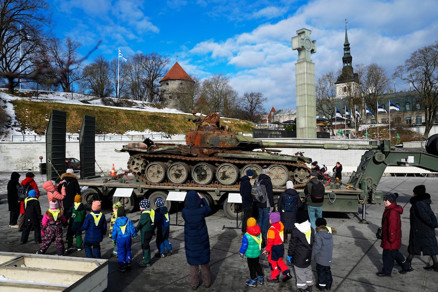 School children look at a destroyed Russian tank on display.