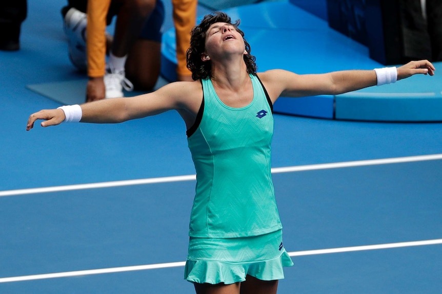 Carla Suarez Navarro with her arms spread out wide after winning her fourth-round match at the Australian Open.