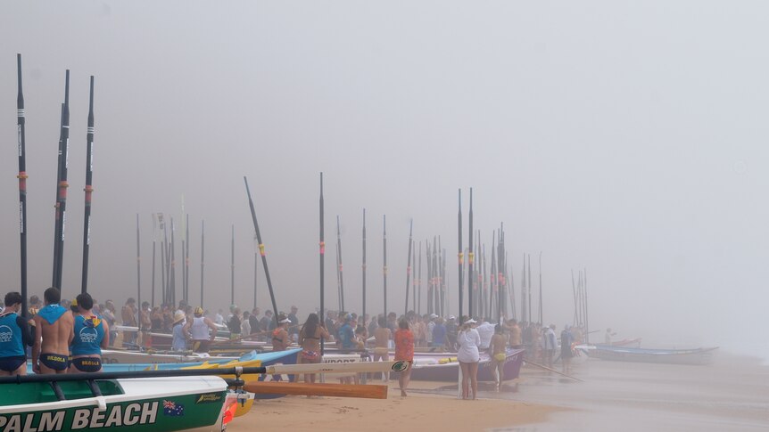 Fog descends on a surf boat carnival at Warriewood Beach during a minute's silence for Dawn Geddes.
