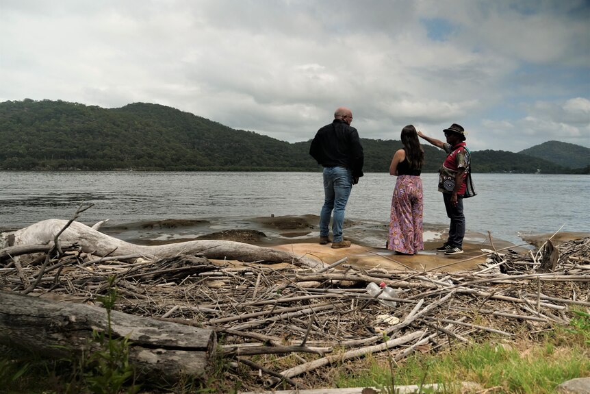 Three people on a rock overlooking Hawkesbury with sticks in foreground