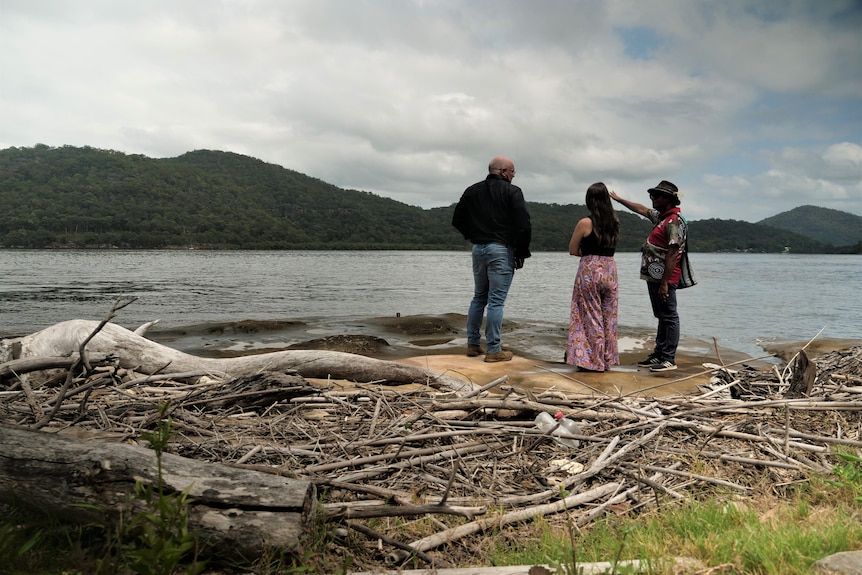 Three people on a rock overlooking Hawkesbury with sticks in foreground