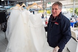 John Colgan displaying bridal dresses inside dry-cleaning store.