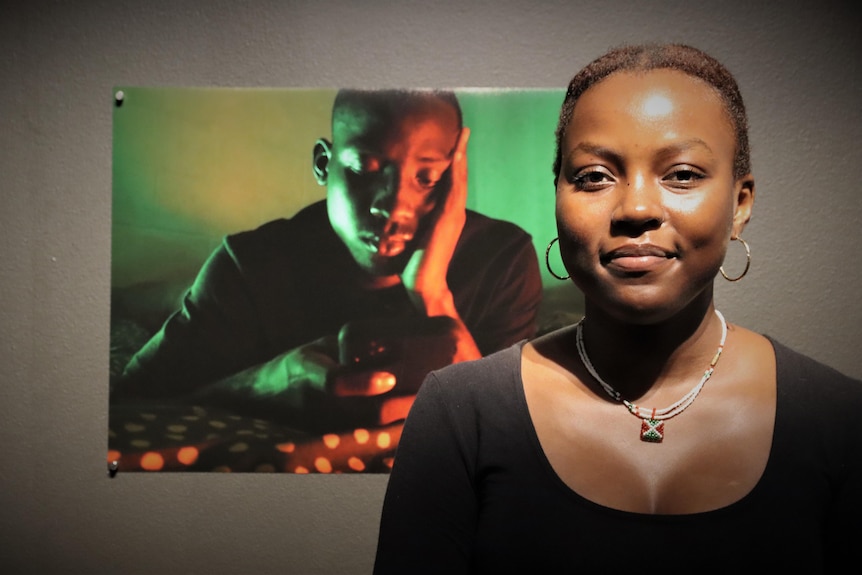 A student artist stands in front of her photography work.