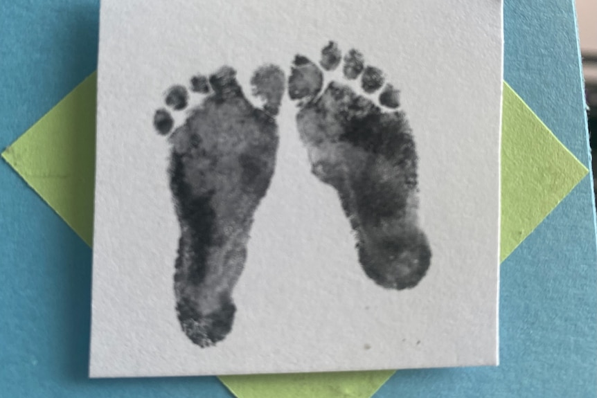 A print of baby feet on a square white sheet of paper.