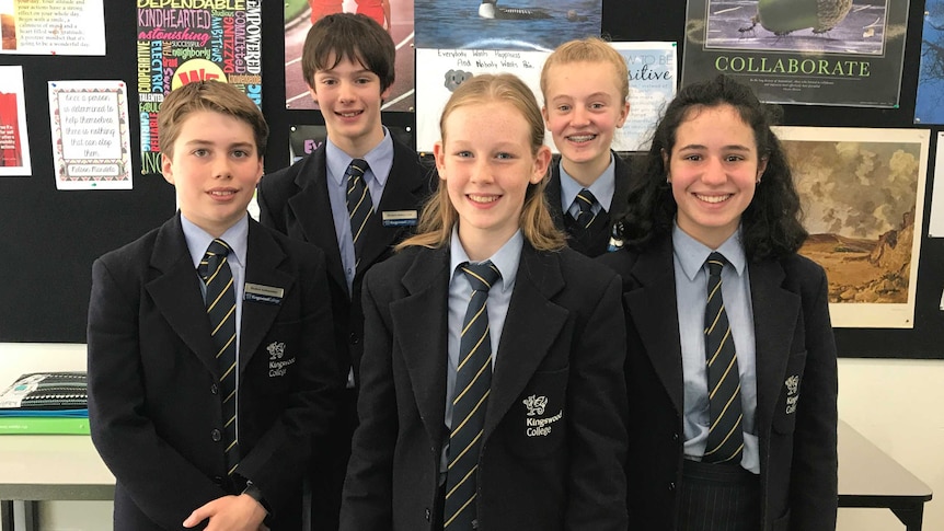 Five male and female students of kingswood college stand in their uniforms looking happy