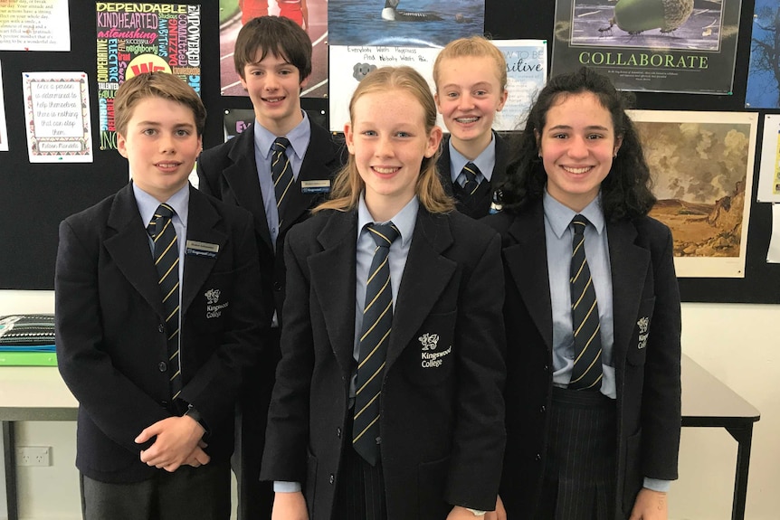 Five male and female students of kingswood college stand in their uniforms looking happy