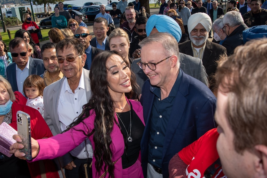 Una mujer con traje rosa se toma una selfie con Anthony Albanese.