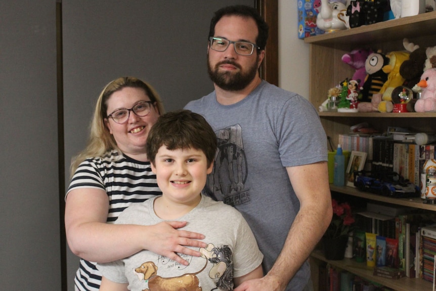 Family photo of man, woman and child standing together.