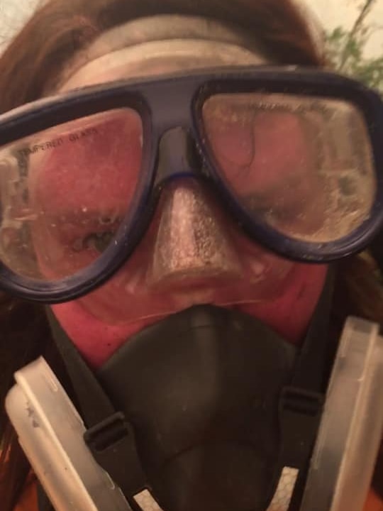 Emma wearing snorkel goggles and respirator, red faced and sweaty