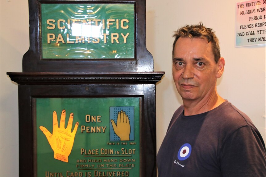 Simon Rogers standing in front of the palmistry machine at his penny arcade  museum 