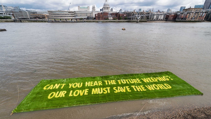 Green banner with yellow words 'Can't you hear the future weeping? Our love must save the world'