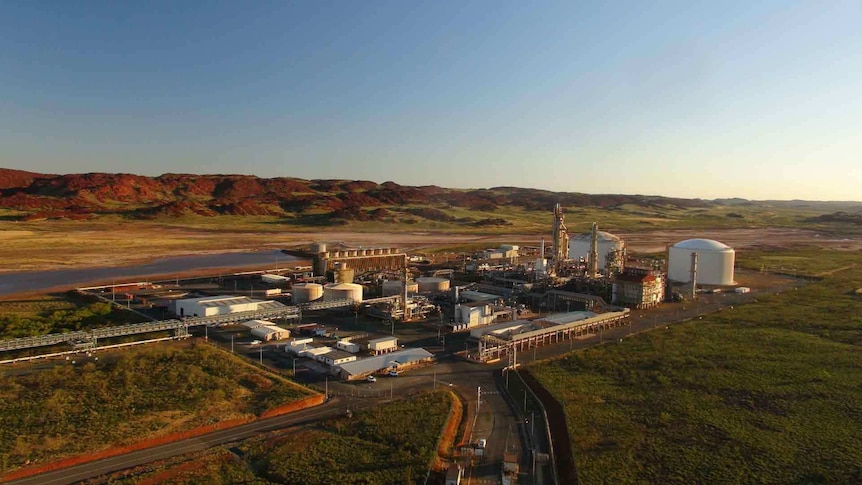 Industrial plant at sunset surrounded by the red rock hills of the Pilbara