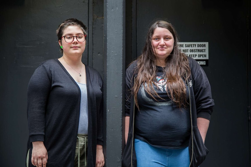 Madelaine (left) and Natasha Anderson stand beside each other near a black wall.