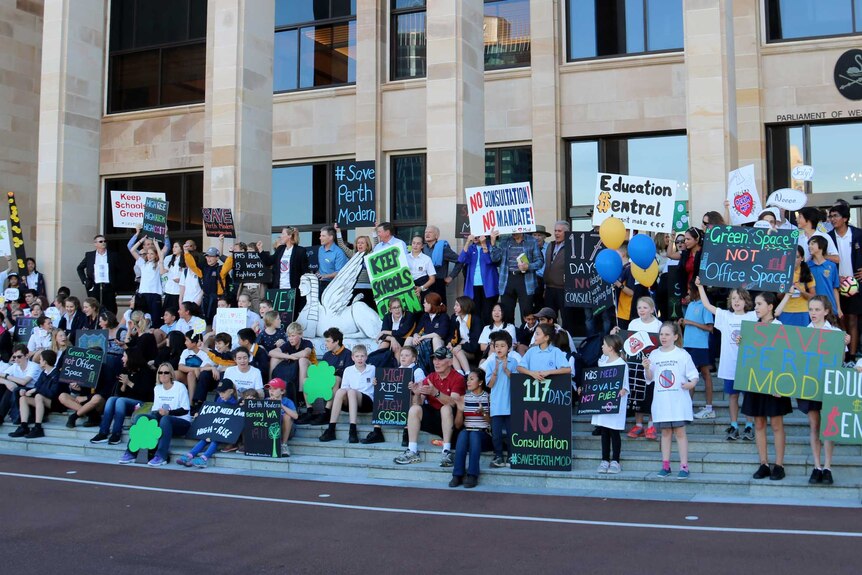 Parents and students from Perth Modern School holding placards on the steps of Parliament.