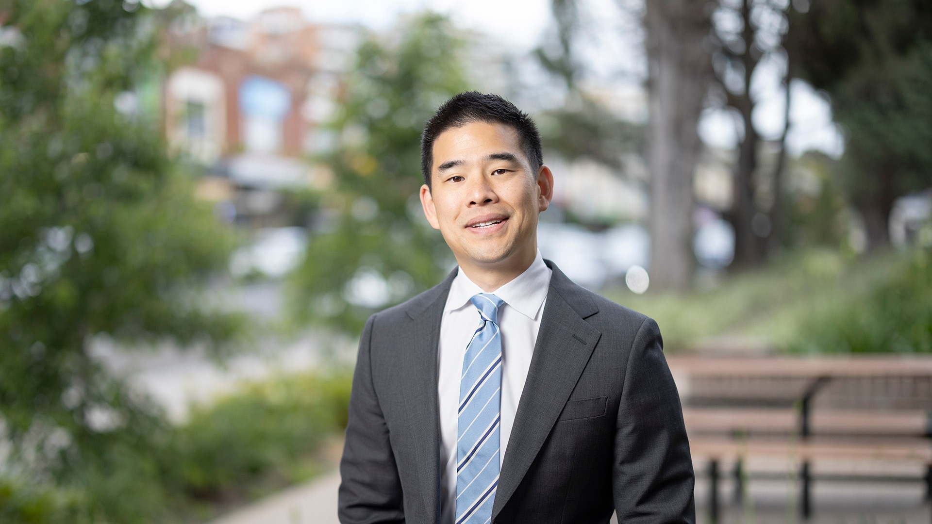 Jeremy Ong in a grey suit and blue tie, smiling outside.