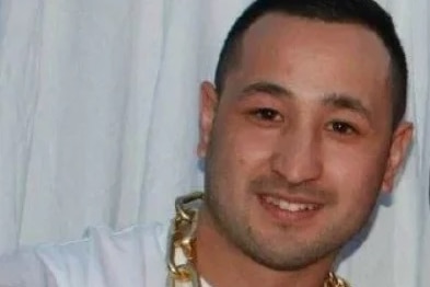 A man in a white shirt wearing a gold chain