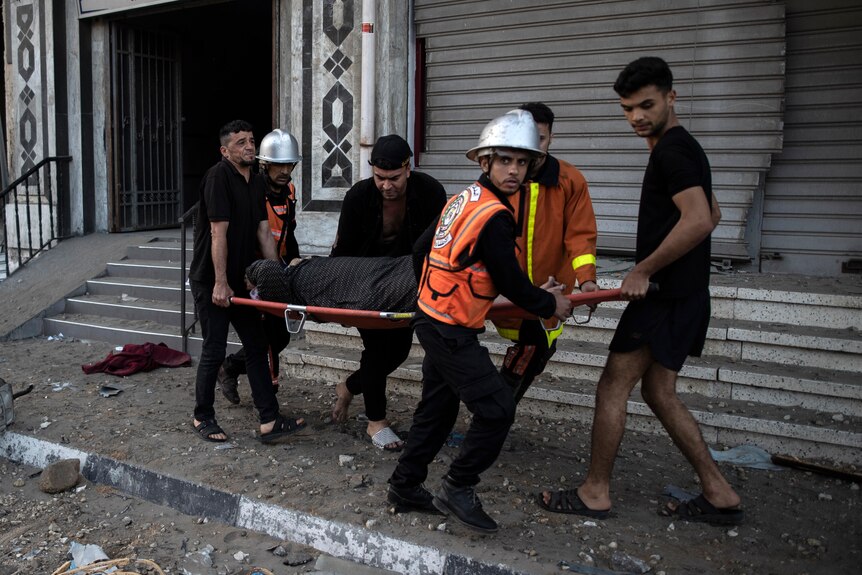 Rescuers evacuate a woman out of a building in Gaza