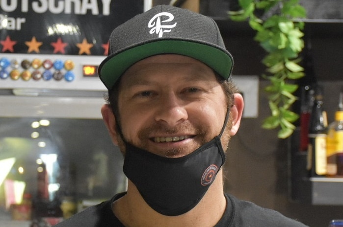 Mathew O'Keefe smiles as he stands behind the beer taps at the bar.