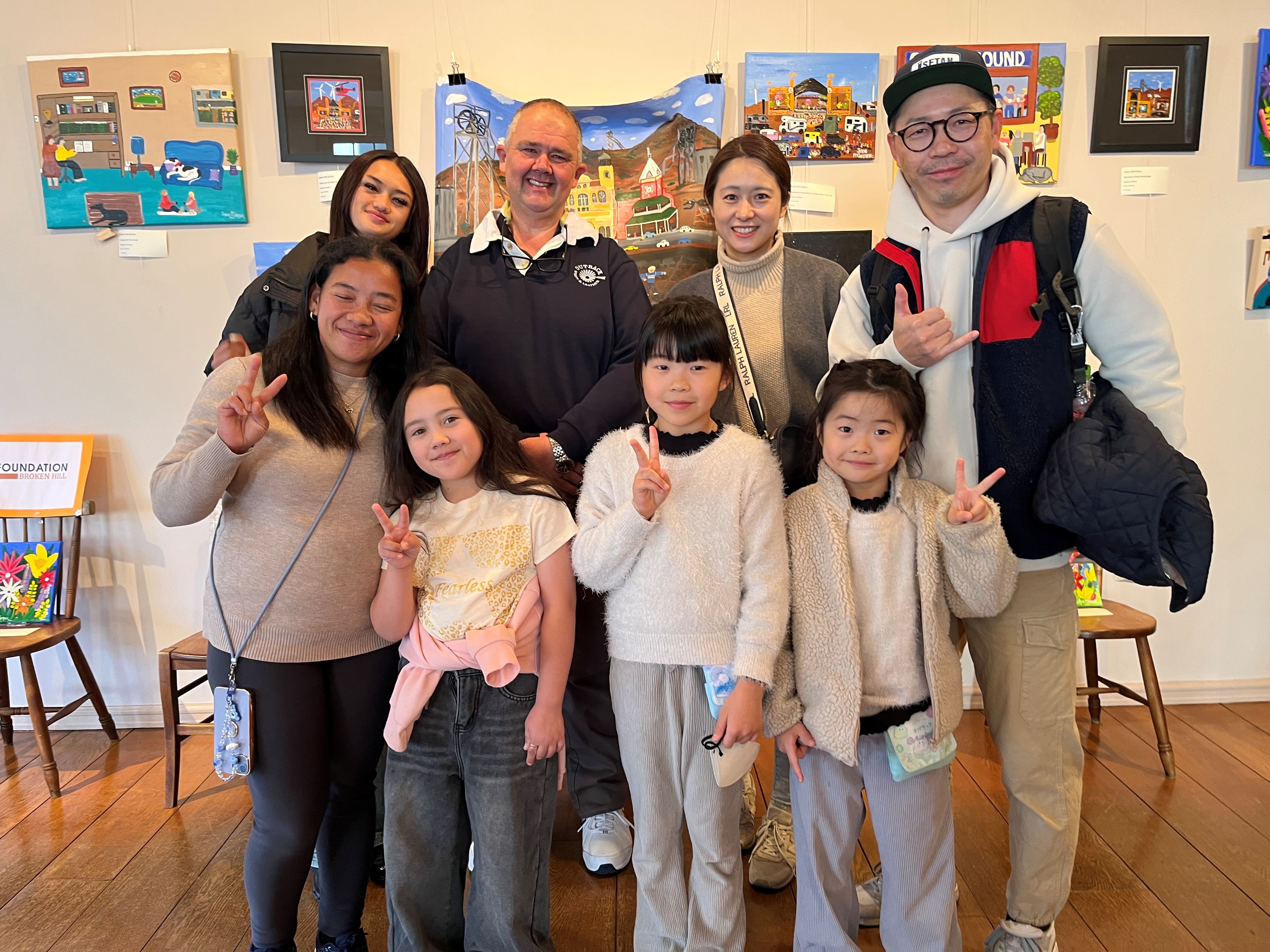 Un grupo de personas se sitúa frente a una obra de arte, hay una mezcla de adultos y niños.