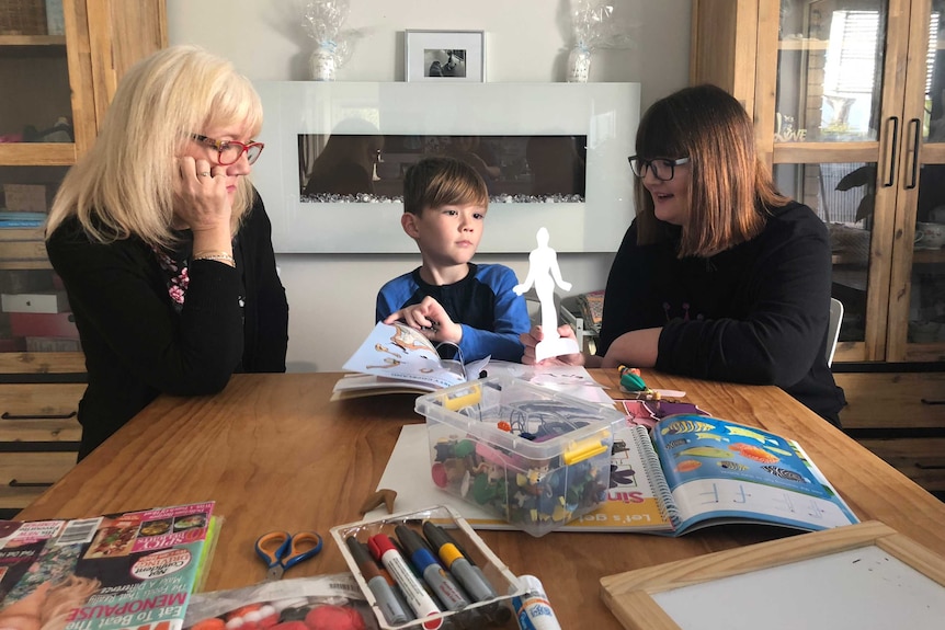 Sarah-Jane and Daisy Cox run through a lesson with eight-year-old Fletcher at the kitchen table.