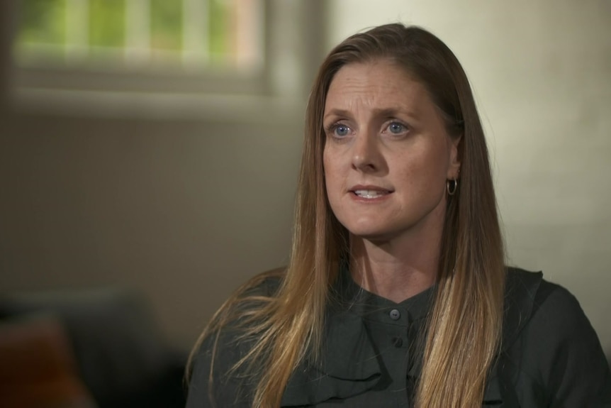 Woman wearing a green shirt speaking to an interviewer. 