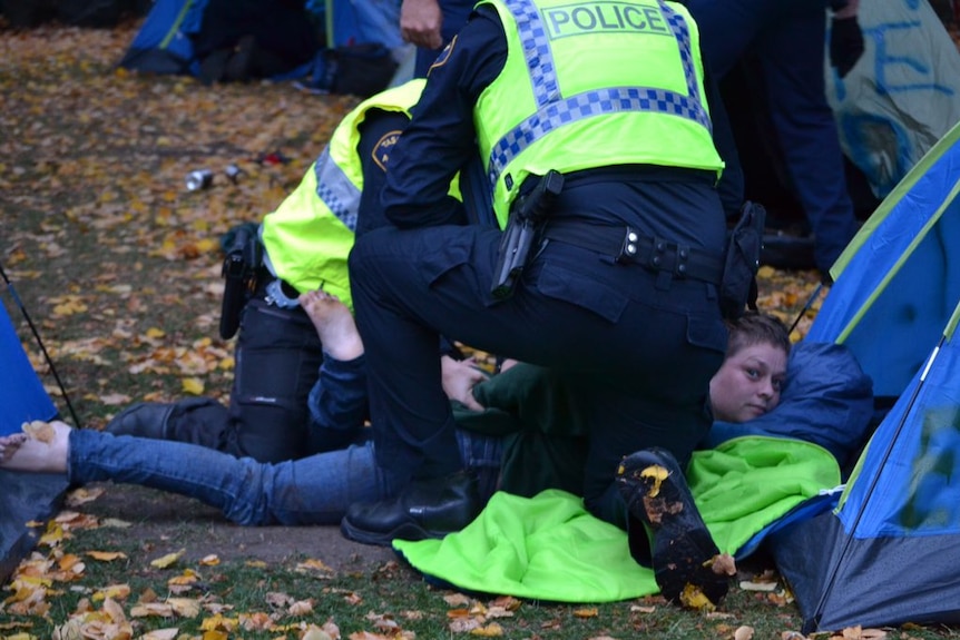 Tasmania Police handcuff a homelessness protester at Parliament in Hobart.