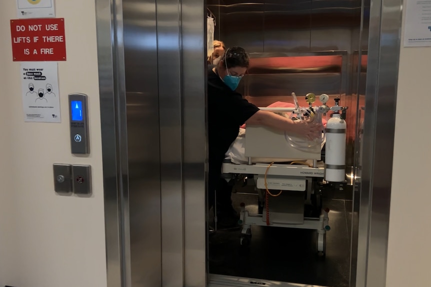 Hospital staff moving a bed into a lift.