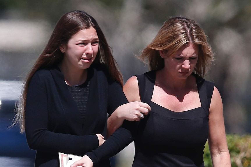 A young girl and a woman embrace as they leave a funeral service for Alyssa Alhadeff.