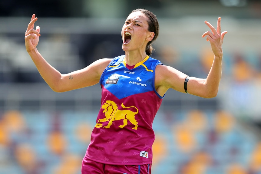 Jesse Wardlaw celebrates a Lions goal with two arms pumped in the air 