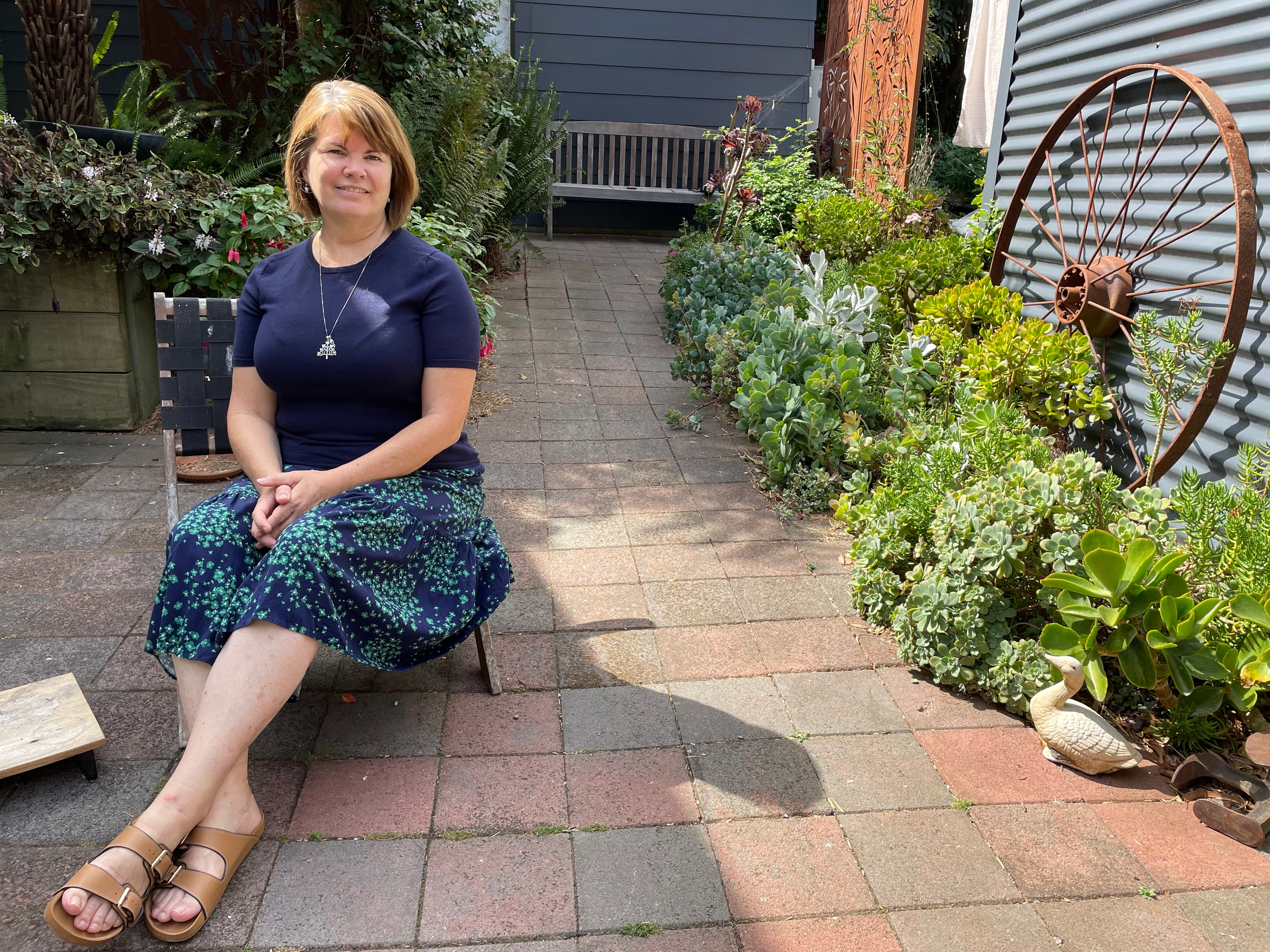 Woman reclining on garden chair in sunlit courtyard 