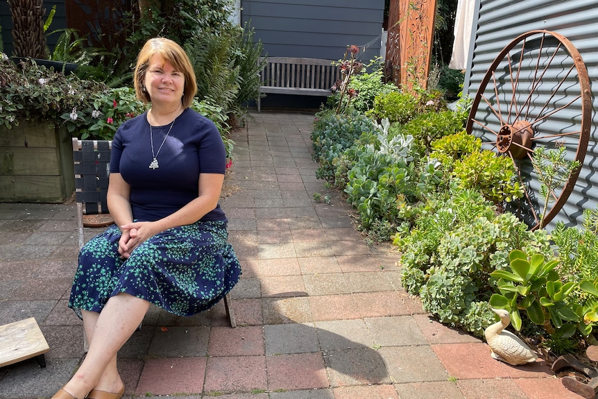 Woman reclining on garden chair in sunlit courtyard 