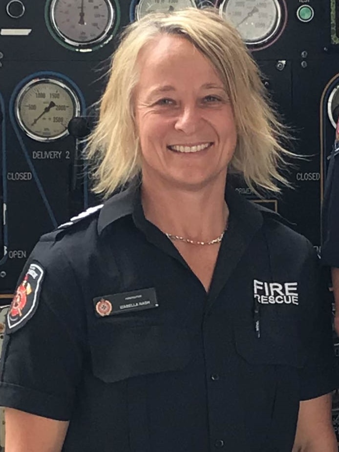 A woman in a firefighting uniform smiles at the camera