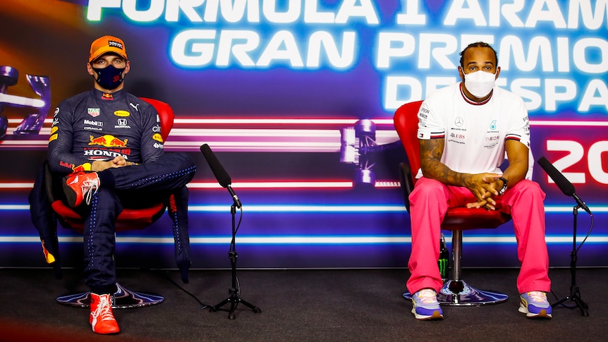 Two formula one drivers sitting side by side in a press conference
