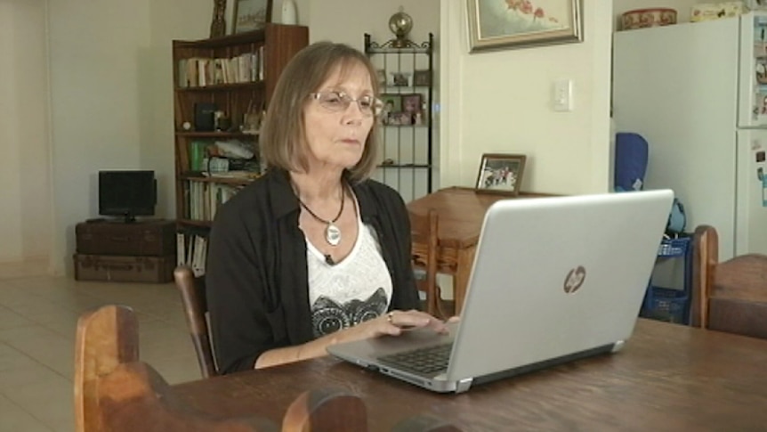 Team Rubber Vine volunteer Gudran McDonald sits at a table on her laptop.