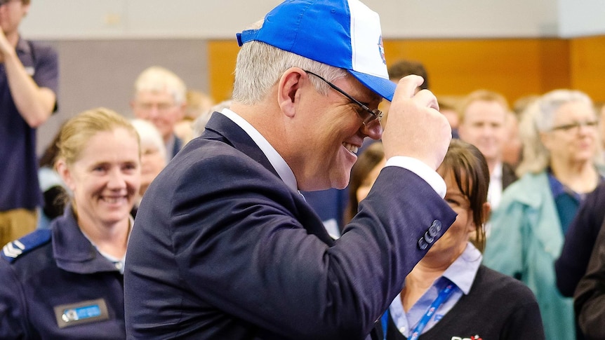 Morrison tries on a blue and white cap