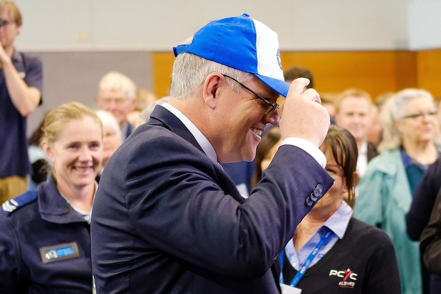 Morrison tries on a blue and white cap