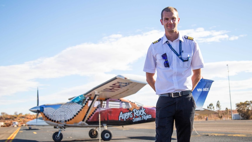 A mans stands in front of a small aircraft