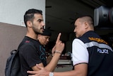 Bahraini football player Hakeem al-Araibi holds his finger up at a police officer