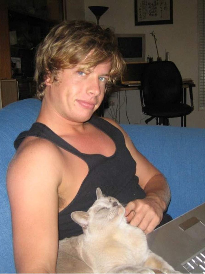 A man, sitting on a sofa, with a cat on his lap.