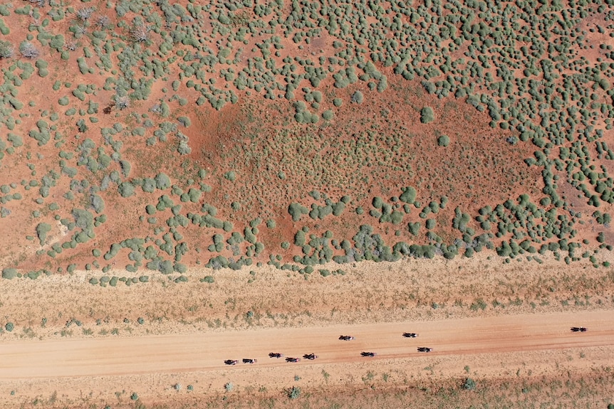 Aerial shot of red landscape and men on motorcycles just a speck