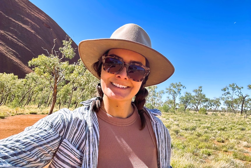 A woman wearing an Akubra hat, sunglasses and long sleeved shirt on a property.