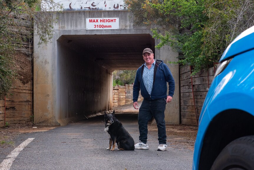a man with dog standing in front of a tunnel under a road