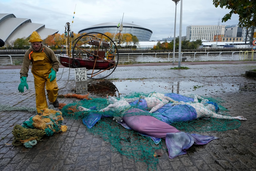 Protesters dressed as merepeople caught in fishing nets protest bottom fishing in Glasgow ahead of COP26.